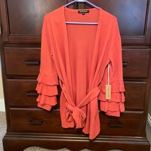 Brand new orange cardigan with ruffled sleeves. Size small.